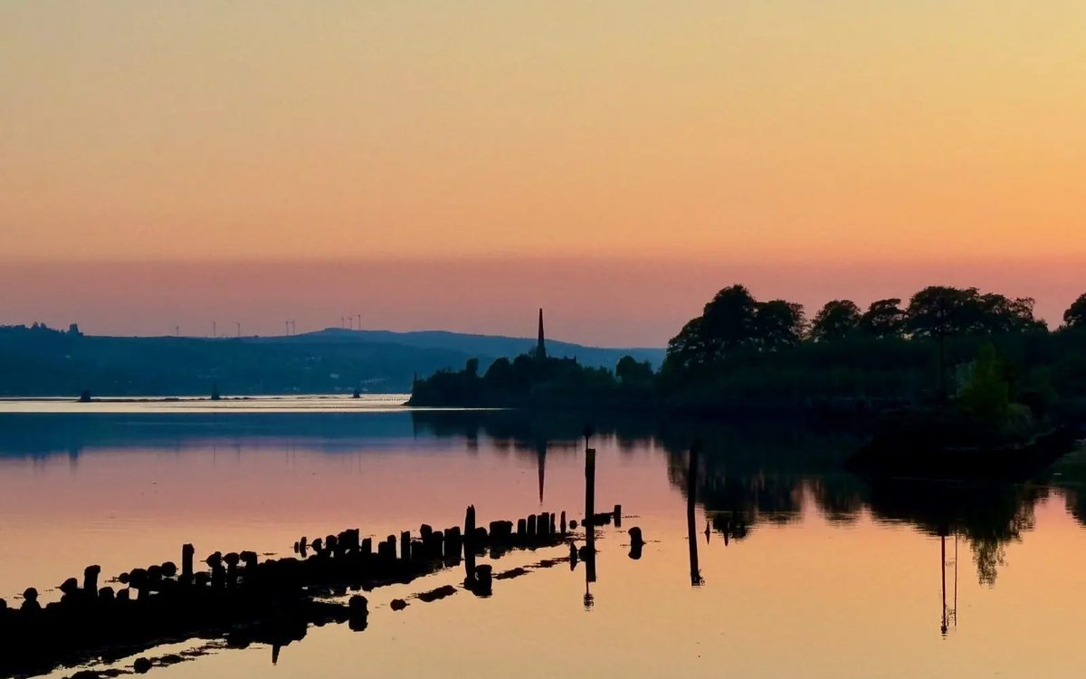 Golden sunset light over still water and an old pier in Scotland