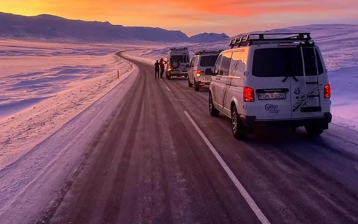 Campervans on a snowy road at sunset in Iceland